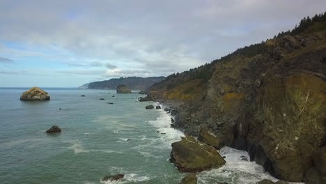 Aerial-drone-footage-of-California's-rocky-coastline-and-evergreen-forest-on-overcast-day