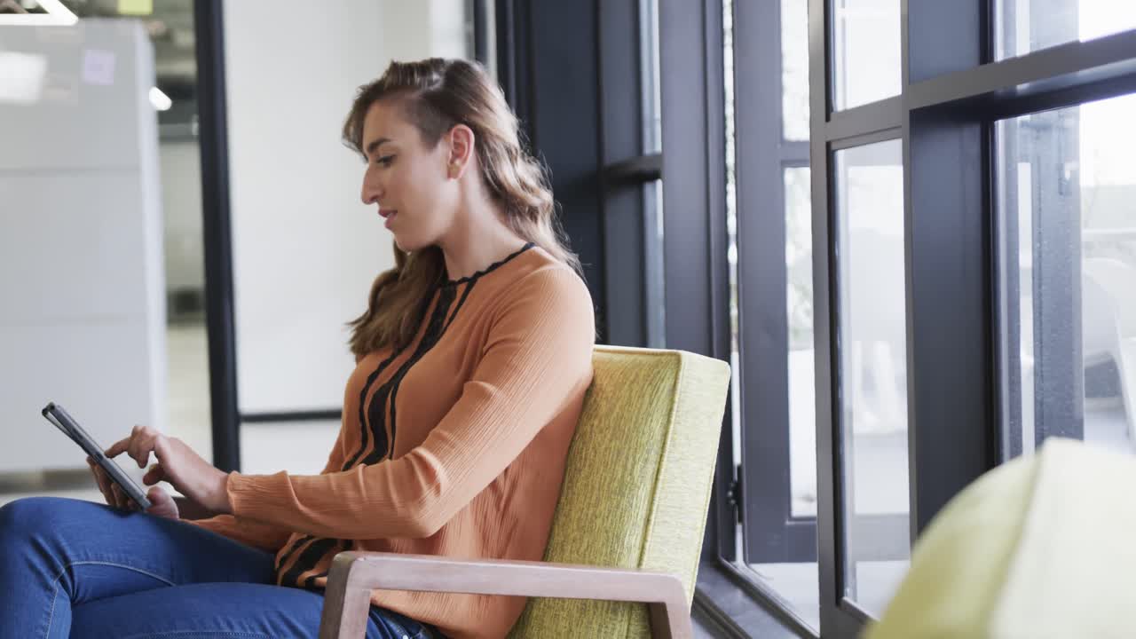 mujer de negocios caucásica feliz usando una tableta en el salón de la oficina, cámara lenta