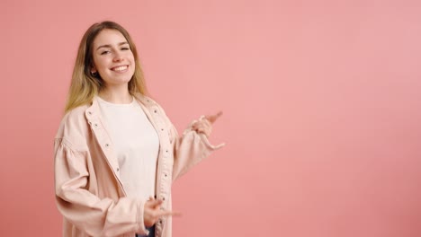 woman gesturing happily on pink background pointing at space