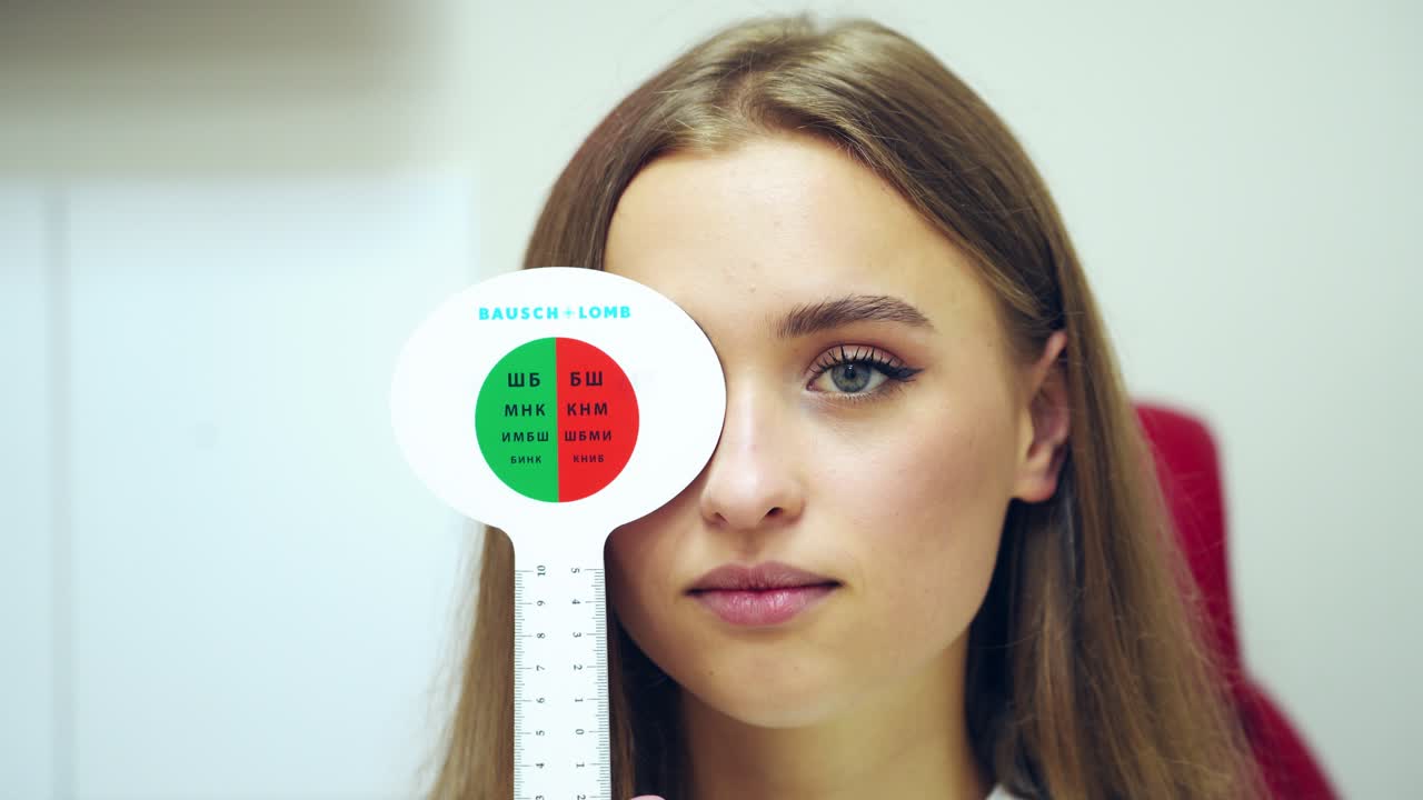 Ophthalmology concept.Young woman covering her eyes one by one during her visit to optometrist. Beautiful female doing vision test with occluder.