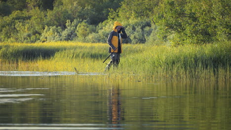 Boy-walking-along-riverside-with-fishing-rod-in-hand-about-to-give-up