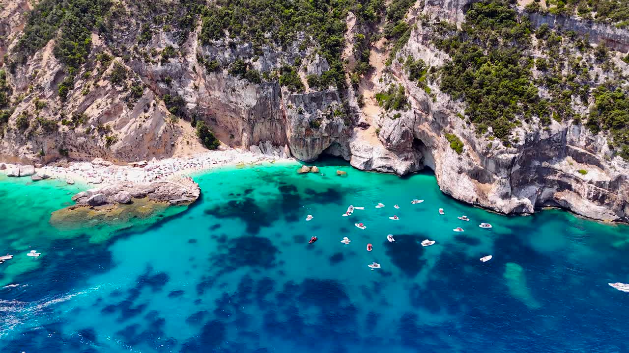 Luftfoto af Cala Mariolu på Sardinien med både, der pryder det turkisblå hav