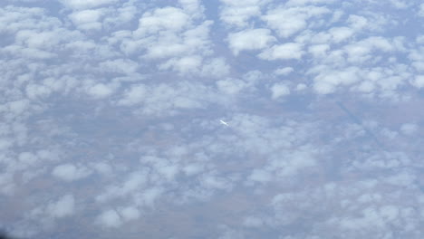 distant airliner flying above clouds seen from cockpit above