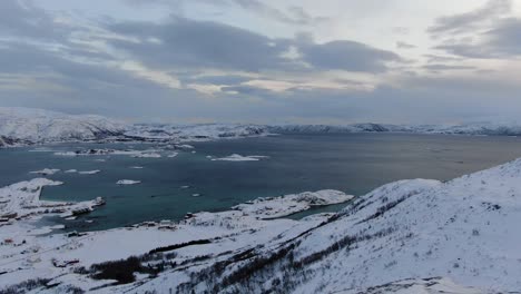 drone view in tromso area in winter flying over a snowy flat islands connected by bridges with small towns in norway