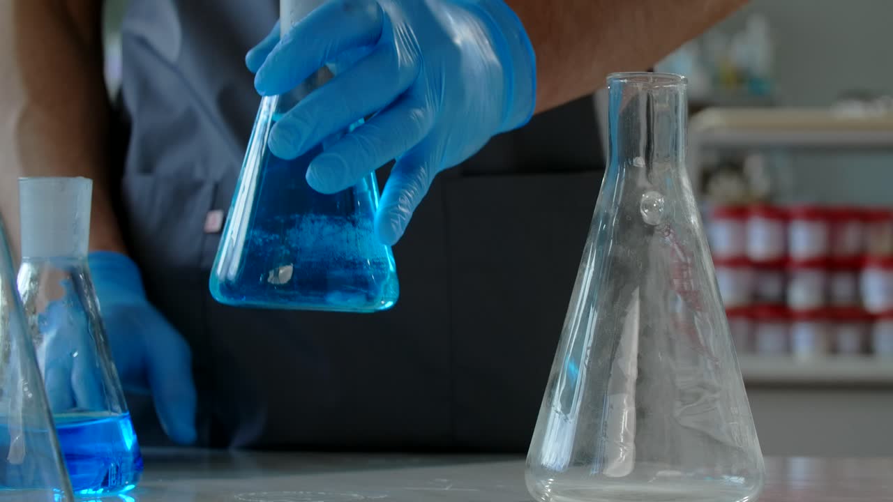 Scientist handling beakers and flasks in a laboratory