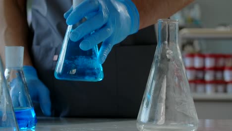 scientist handling beakers and flasks in a laboratory
