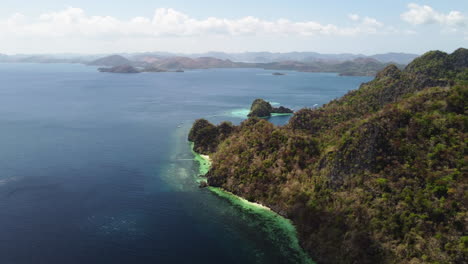 Cinematic-aerial-footage-of-the-cliffs-of-Palawan-while-flying-forward-revealing-beautiful-beaches-and-lagoons-with-boats-in-focus,-Philippines,-Asia,-Drone