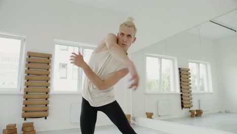 a man in a white tank top and black pants is dancing in a studio