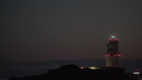 airplane landing at night near air traffic control tower