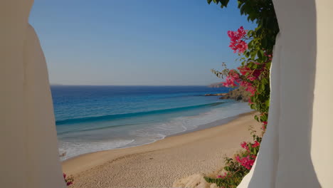 idyllic beach view through a white archway with bougainvillea