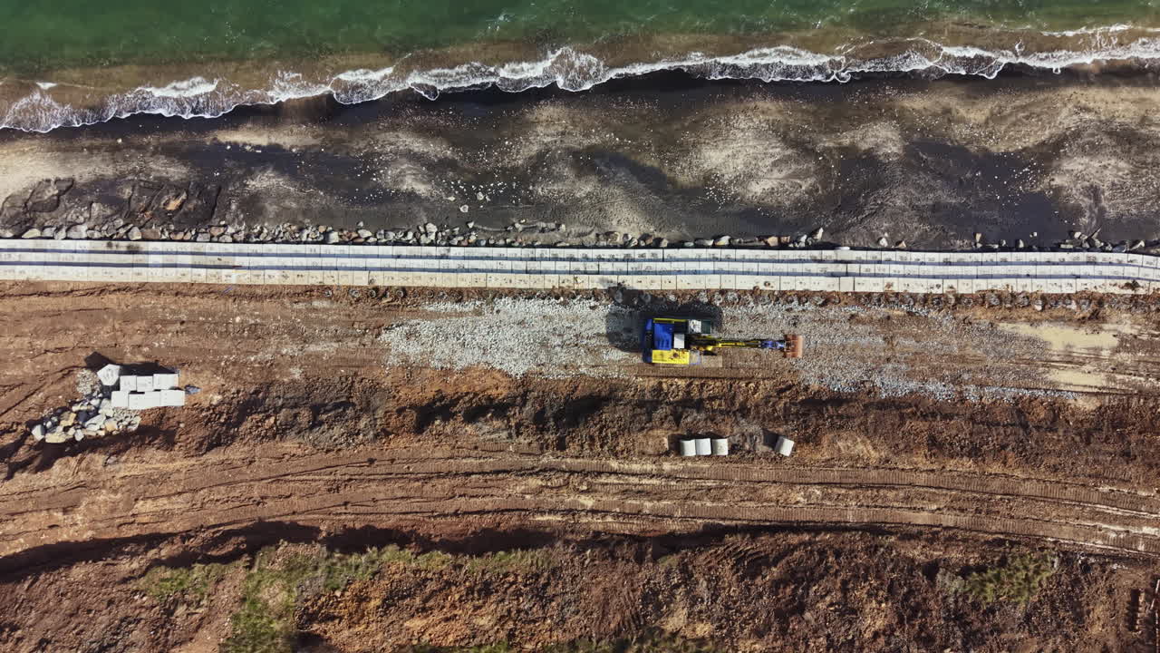 Lavori di costruzione su un'area balneare con macchinari e materiali in loco durante le ore diurne vicino alla costa.