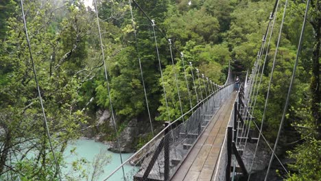 Cámara-Lenta:-Una-Persona-Se-Para-En-Un-Puente-Colgante-Sobre-El-Río-Glaciar-En-El-Desfiladero-De-Hokitika,-Nueva-Zelanda