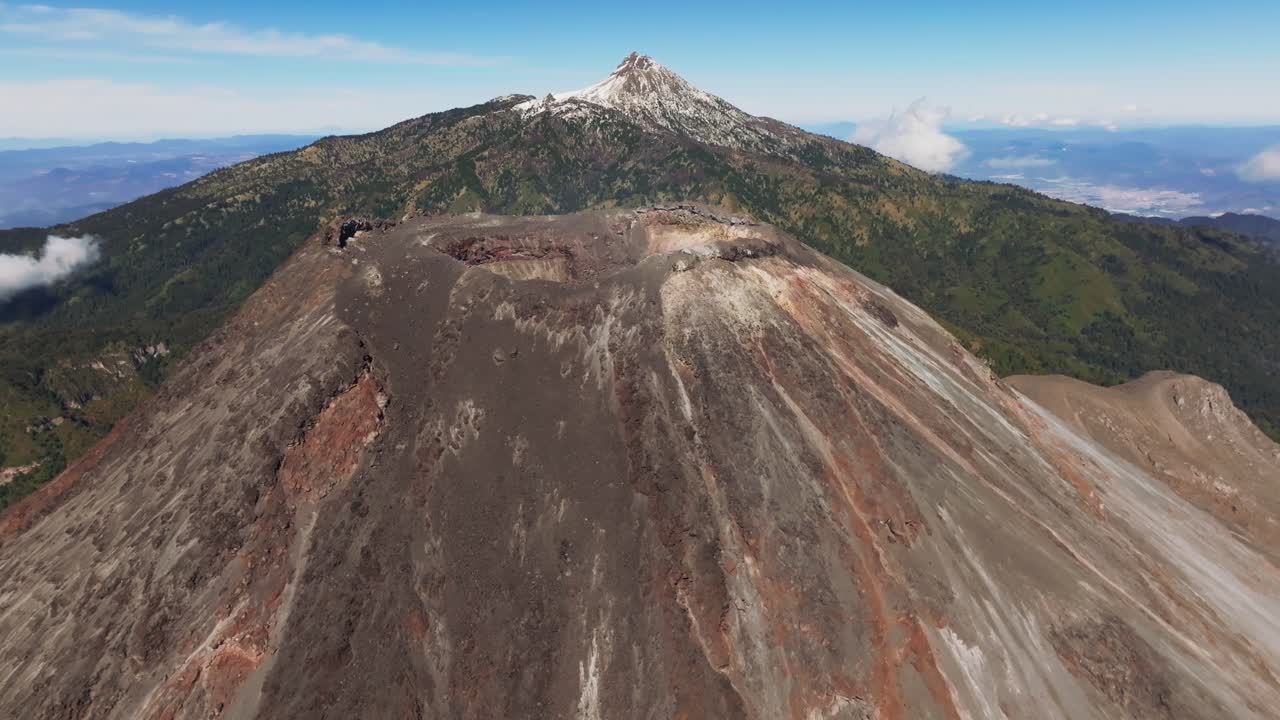 Establishing shot of the Colima Active Volcano's Crater. Backward drone flight reveals the Zapotepetl or Nevado de Colima snowed peak