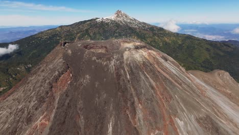 establishing shot of the colima active volcano's crater. backward drone flight reveals the zapotepetl or nevado de colima snowed peak