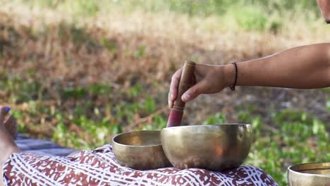 Person-singing-a-golden-Tibetan-bowl,-over-the-body-of-a-woman