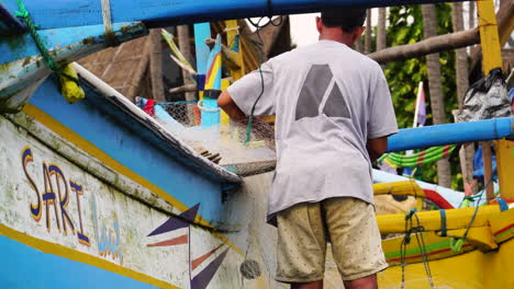 Fisherman-arranging-net-next-to-Indonesian-outrigger-canoe