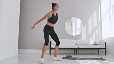 beautiful slim woman in thirties with fair complexion does morning strenth and aerobic burpee exercises in modern airy room