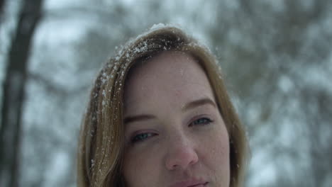 Woman-outside-in-slow-motion-winter-snow-looks-at-camera-as-snowflakes-fall-in-cinematic-slow-motion