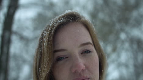 woman outside in slow motion winter snow looks at camera as snowflakes fall in cinematic slow motion