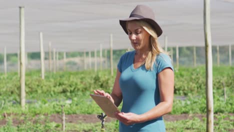 Video-of-caucasian-woman-with-laptop-standing-in-greenhouse