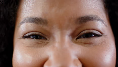 Portrait-of-casual-biracial-businesswoman-smiling-in-office,-slow-motion-with-copy-space