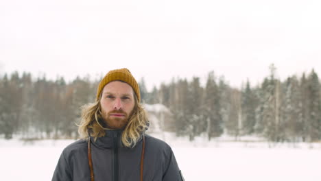 Front-View-Of-Man-In-Winter-Clothes-Looking-At-Camera-In-Winter-Forest