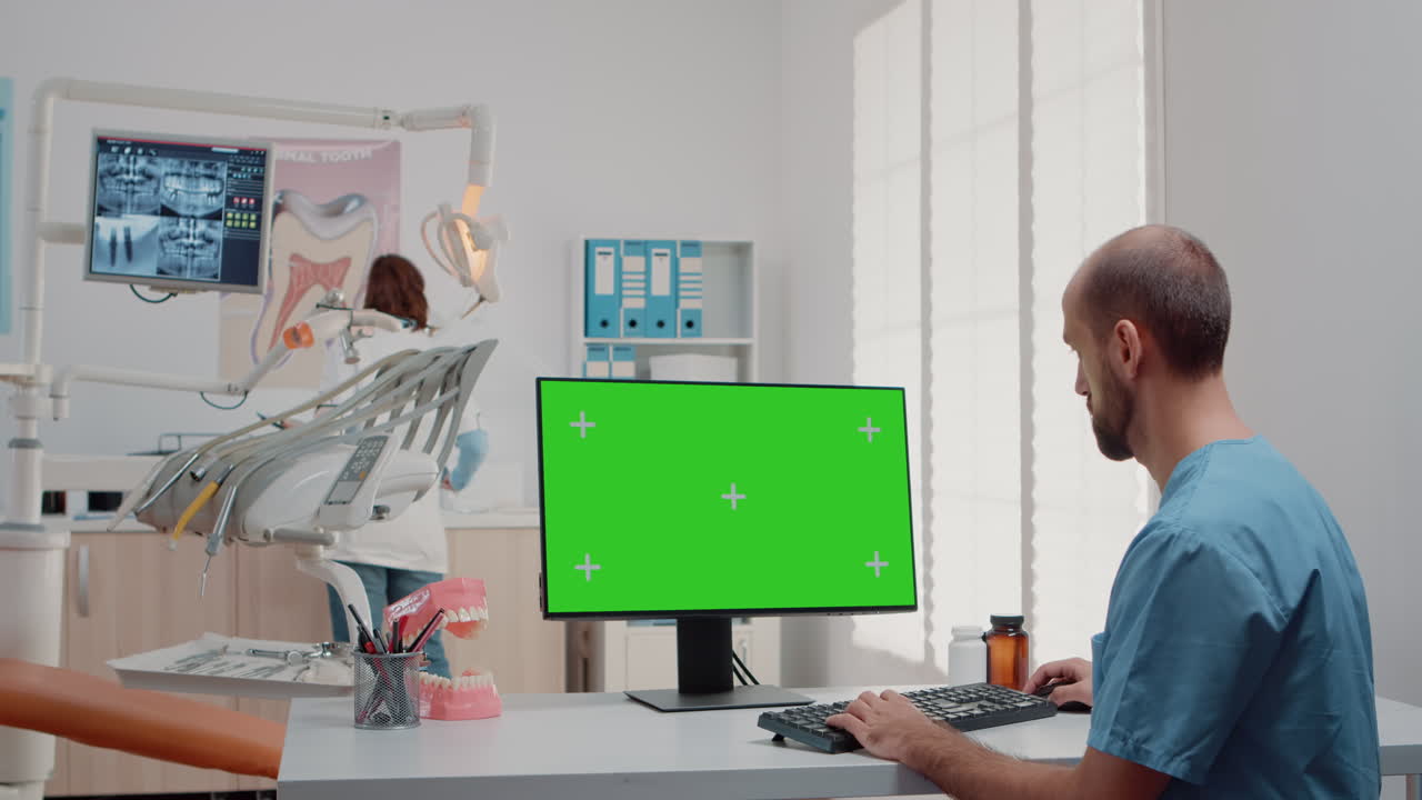Man working with keyboard and computer with green screen
