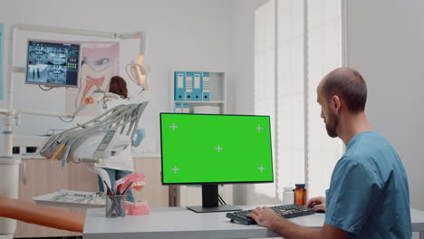 hombre trabajando con teclado y computadora con pantalla verde