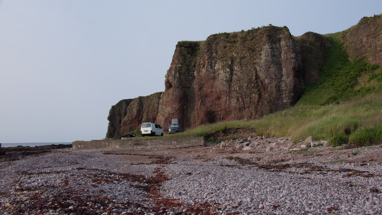 Wide shot of the cliffs at the old harbour at Auchmithie with camper vans parked for the night