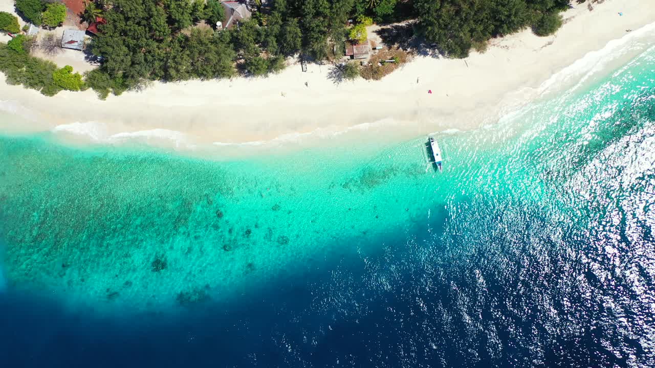 Isola alle Maldive - Barca ormeggiata sulla riva di un'isola paradisiaca tropicale orlata da alberi verdi e sabbia bianca, circondata da acqua oceanica blu scuro - Ripresa aerea
