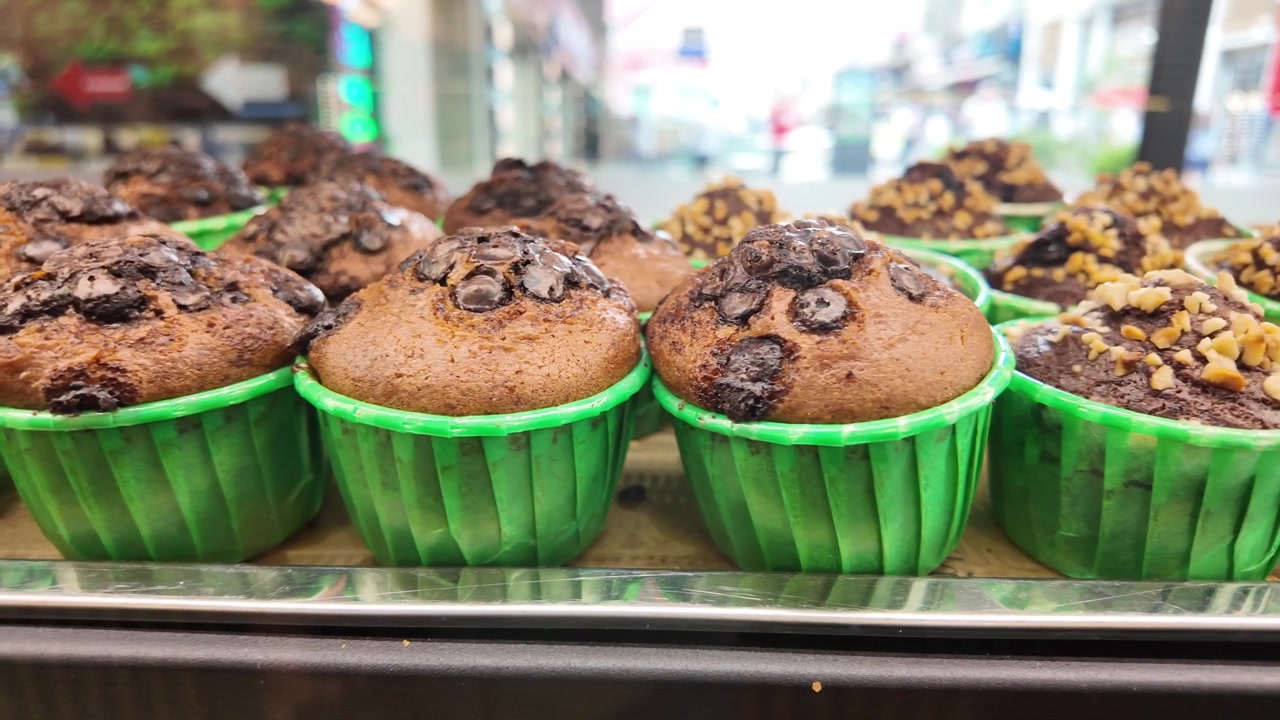 Primo piano di muffin appena sfornati con gocce di cioccolato e noci.