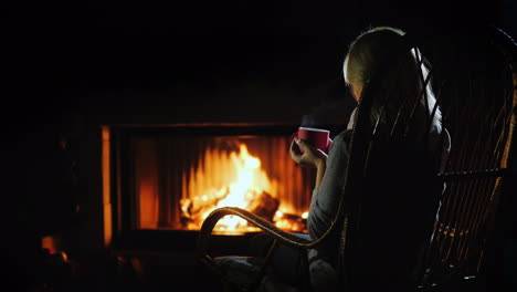 middle-aged woman drinks hot tea by the fireplace winter escape concept