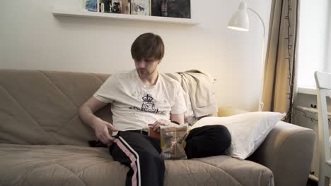 man relaxing on couch eating chips