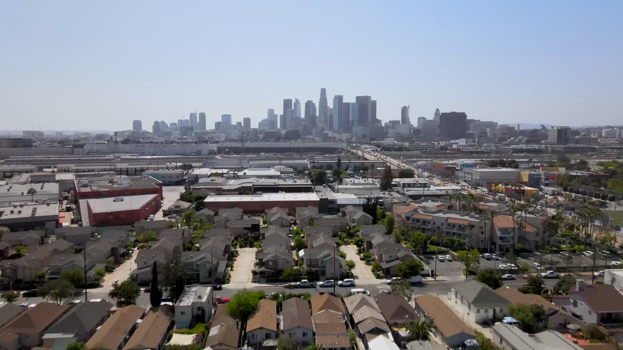 Dynamic drone footage pushes into a vibrant LA neighborhood, with the iconic downtown skyline standing majestically in the background.