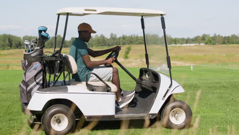 Hombre-Afroamericano-Conduciendo-Un-Coche-En-El-Campo-De-Golf.