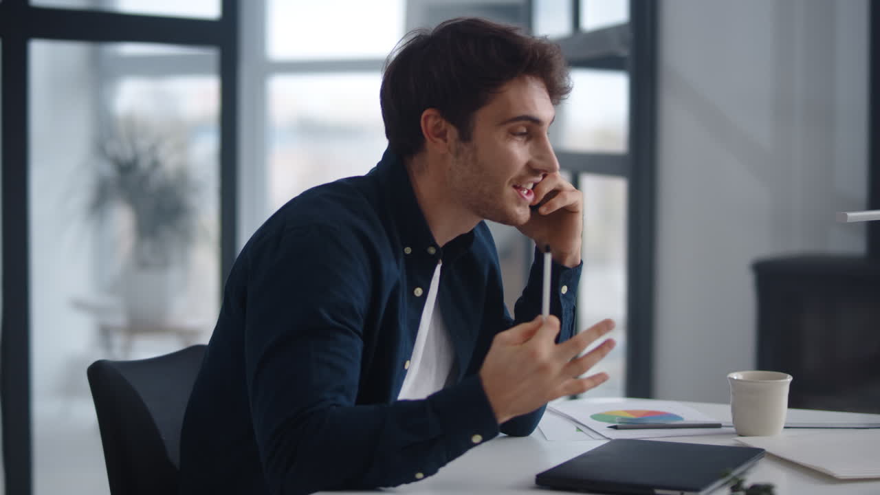 Close-up view of cheerful businessman talking smartphone emotionally at home office