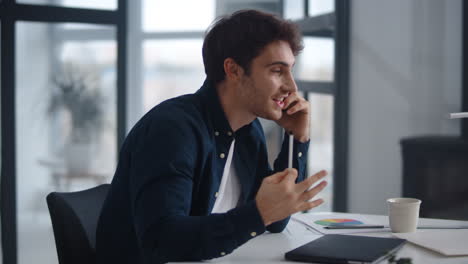 vista de primer plano de un hombre de negocios alegre hablando con su teléfono inteligente emocionalmente en la oficina de su casa