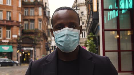 male wearing a medical mask looking at camera on a busy london street