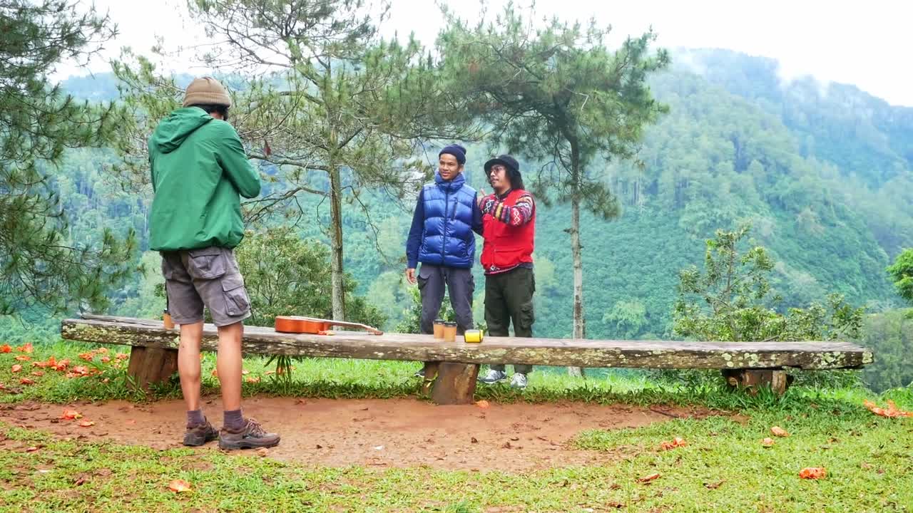 Friends enjoying scenic mountain during hiking trip taking pictures together nearby wooden bench