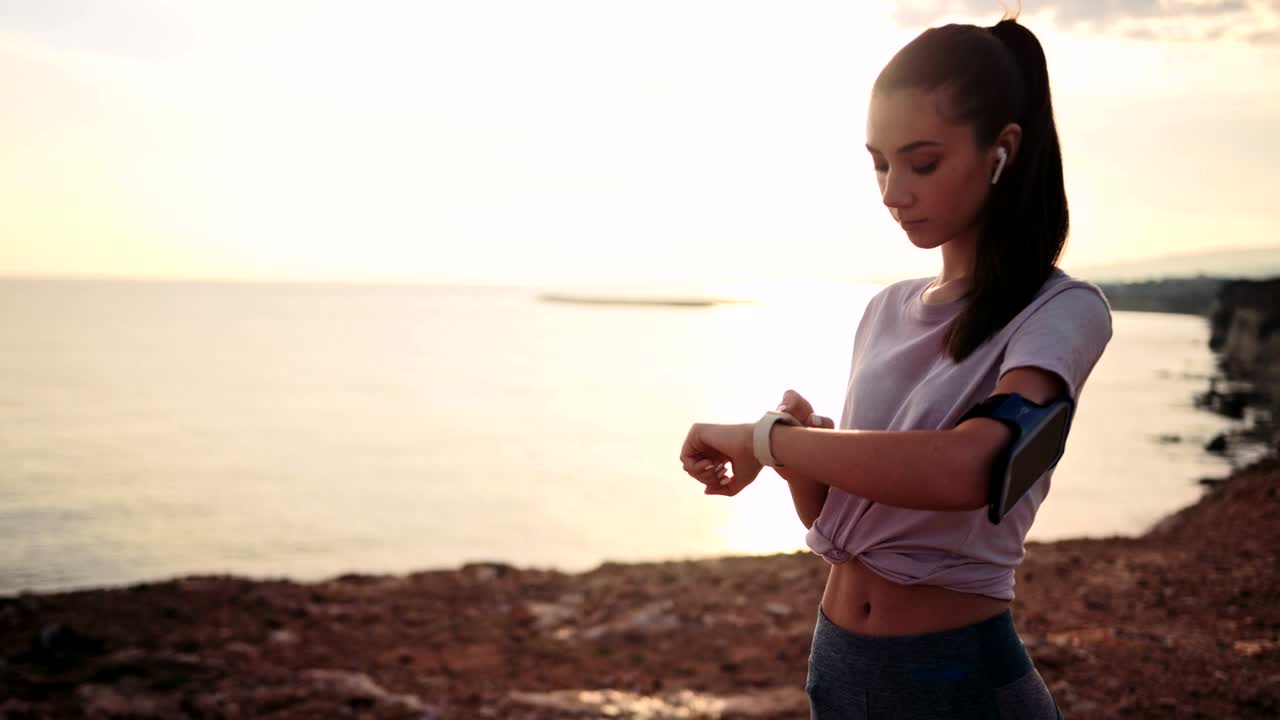 Mujer monitoreando su progreso de fitness en un smartwatch al aire libre al atardecer