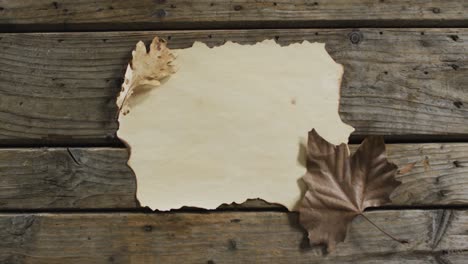 close up view of paper with copy space and autumn leaves on wooden surface