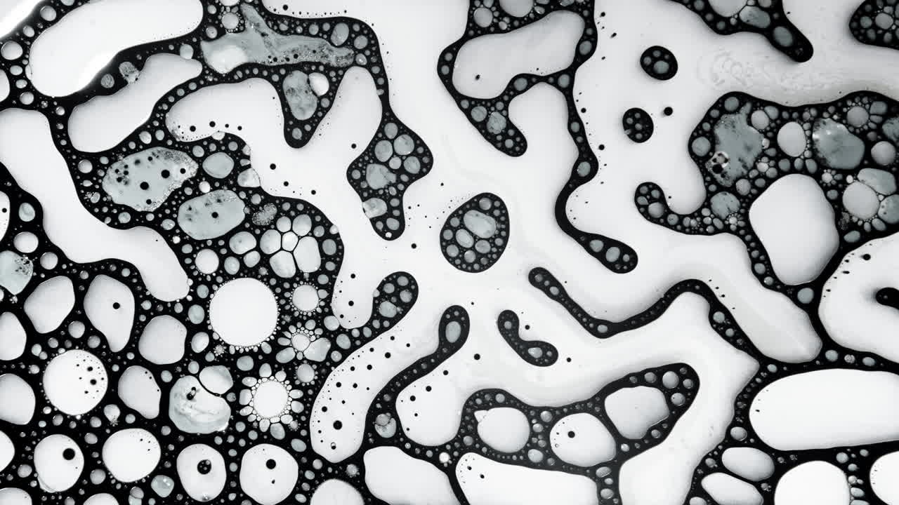 Abstract macro shot of black liquid patterns forming organic, cellular shapes on a white surface