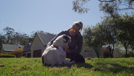 girl in sunglasses playing with australian bulldog on grass