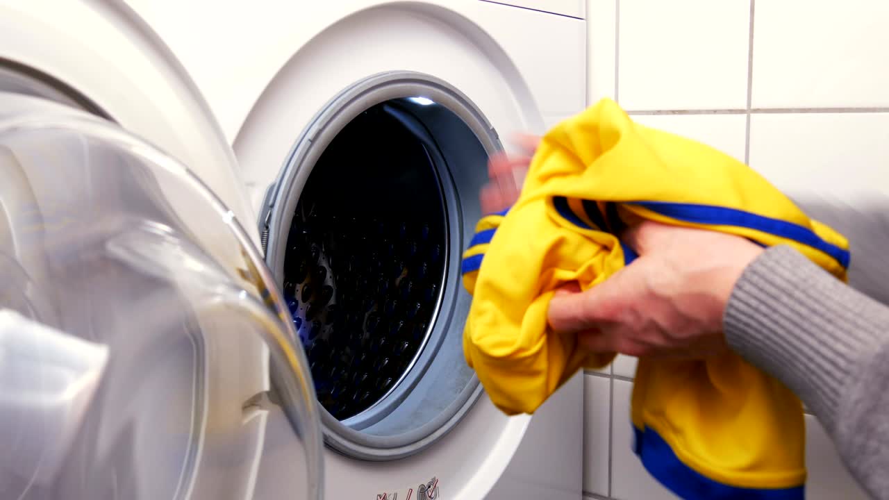 Putting a football shirt of a child into the washing machine