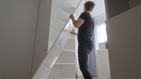 young man struggle to install closet doors, back view