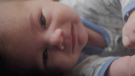 Baby-boy-laying-down-on-the-couch-on-his-side-looking-at-the-camera