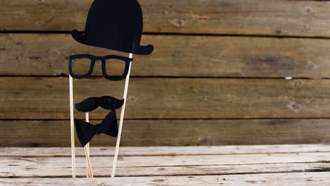 corbata de pajarita, gafas y bigote falso dispuestos en una tabla de madera