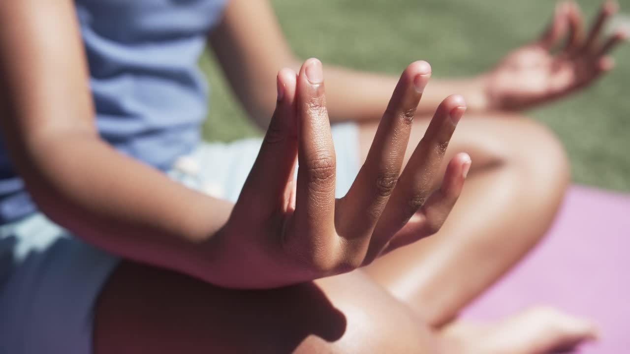 Person's right hand is resting on knee and shifting with breath on pink mat during meditation