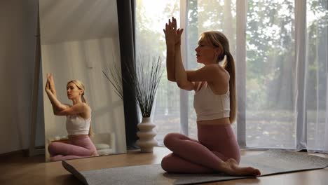 a beautiful woman practices yoga in front of a mirror while sitting on the floor a beautiful woman practices yoga in front of a mirror while sitting on the floor