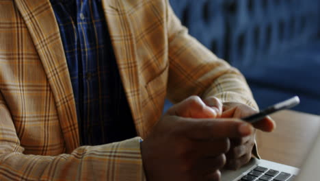 Senior-businessman-using-his-phone-while-working-on-the-laptop-4K-4k